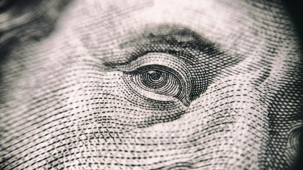 Close-up of an eye engraved on a dollar bill, suggesting profit and cash cows