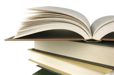 Open book stacked on other books, suggesting early storytelling and writing inspiration